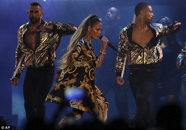 Snazzy back-up dancers: Here the mother of two wore a long black and gold coat