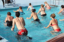 Группа людей в купальных костюмах педалирования на металлических каркасах в мелком бассейне